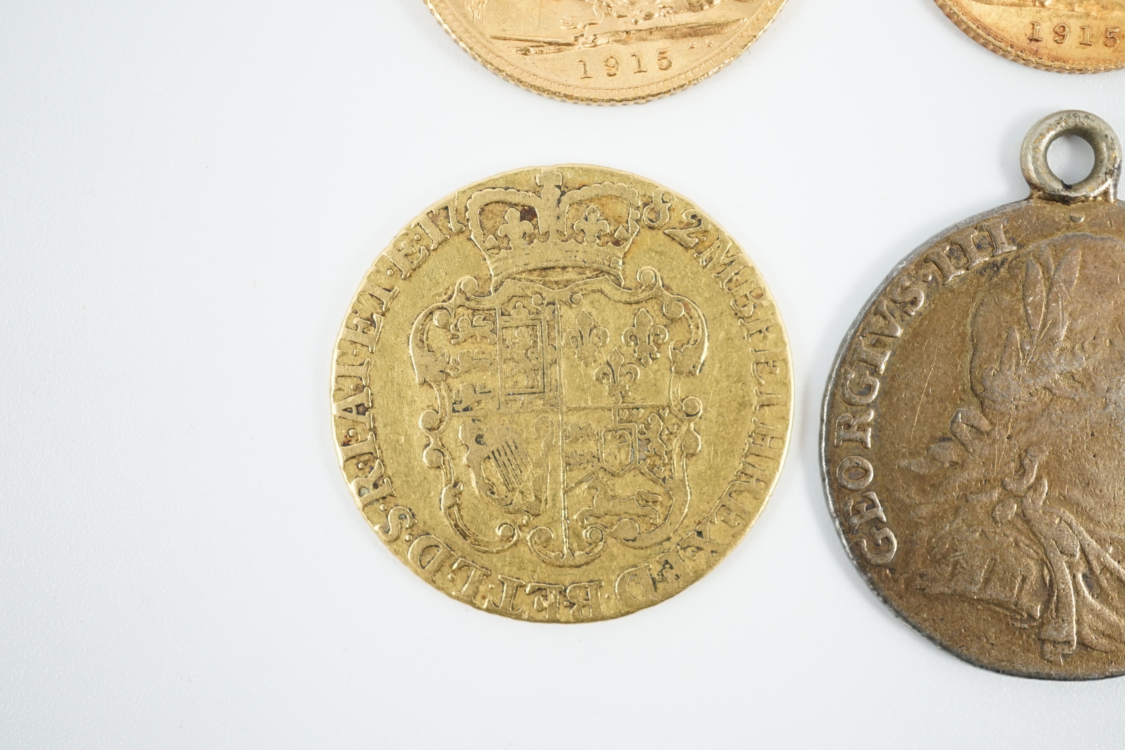 A George V 1915 gold sovereign and a 1915 gold half sovereign, a George III 1782 gold guinea(worn) and a George III 1787 shilling, with pendant mount.